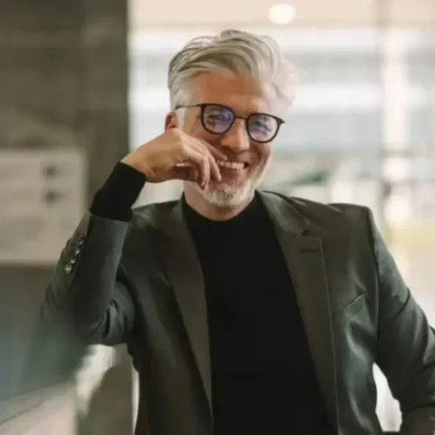 Nasmiješen muškarac sa slušnim aparatom u poslovnom okruženju